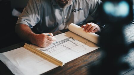 man sketching blueprints