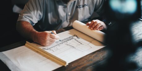 man sketching blueprints