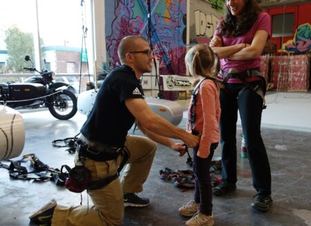 man helping child with climbing harness